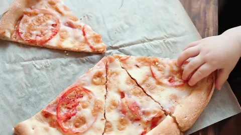 The child steals pizza from the table until the adults see Video stock 131521251