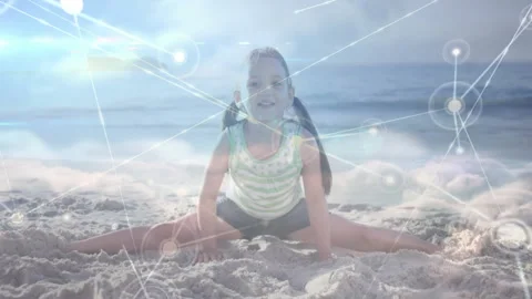 Child stepping into side split on beach, activating glowing network overlay for Stock Footage 310667925
