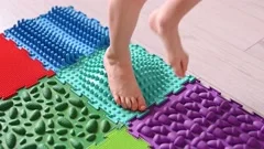 Toddler on baby foot massage mat. Exercises for legs on orthopedic