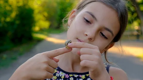 A child is studying a snail in the park. Selective focus. Stock Footage 213634517