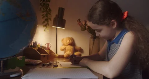 Child is studying while sitting at home in rays sun in room. Kid in morning Stock Footage 263801716