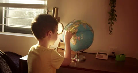 Child is studying while sitting at home in rays sunset in room. Kid in morning Stock Footage 263866596