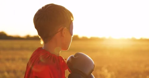 Child Superhero in making. Boy in vibrant costume and boxing gloves trains at Stock Footage 330008688