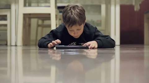 Child surfing in internet with a tablet lying on the floor Stock Footage