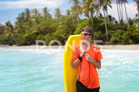 Child surfing on tropical beach. Surfer in ocean. Stock Photos