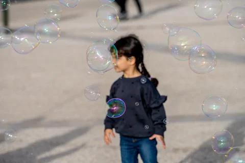 Child surrounded by floating soap bubbles in Lisbon Stock Photos