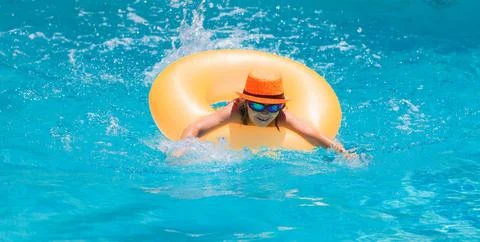 Child in swimming pool on inflatable ring. Kid swim with orange float. Water toy Foto stock