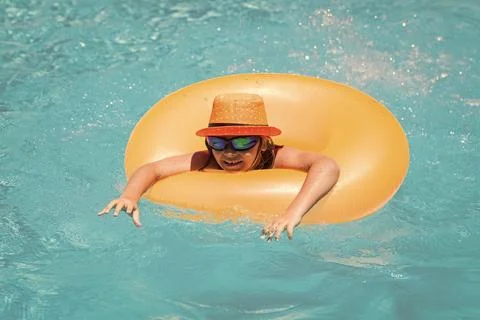 Child in swimming pool on inflatable ring. Little boy swim with orange float 스톡 사진