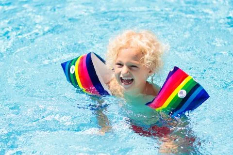 Child in swimming pool. Kid with float armbands. Stock Photos