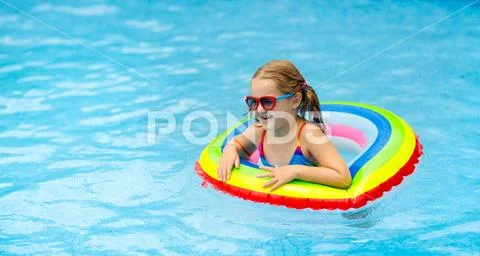 Child in swimming pool on toy ring. Kids swim. Stock Photos