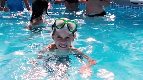 Child swimming in a swimming pool while people practicing water aerobics Stock Footage 136814097