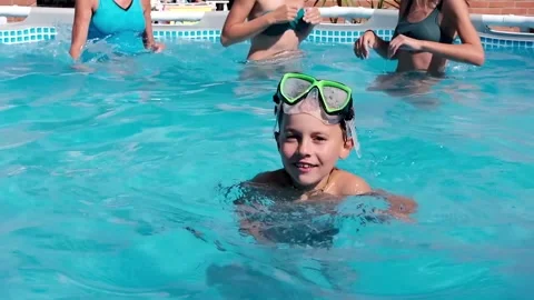 Child swimming in a swimming pool while people practicing water aerobics Stock Footage 136814098