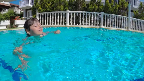 The child swims in the pool in the sun. Video stock 231924821