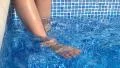 Child swinging feet in swimming pool HD Footage