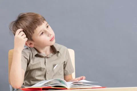 The child at the table is doing homework. Primary school student at a desk with Stock Photos