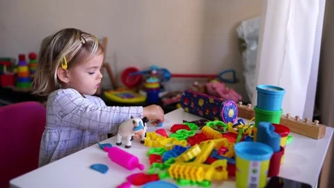 Child at table enjoying leisure time playing with toys Stock Footage 280798357