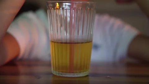 The child at the table, wearing a white t-shirt, is drinking apple juice. Stock Footage 251723720