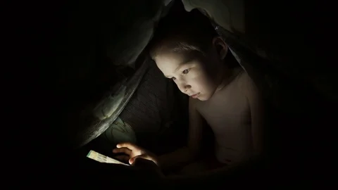 Child with a tablet on the bed, under the blanket Stock Footage 74963248
