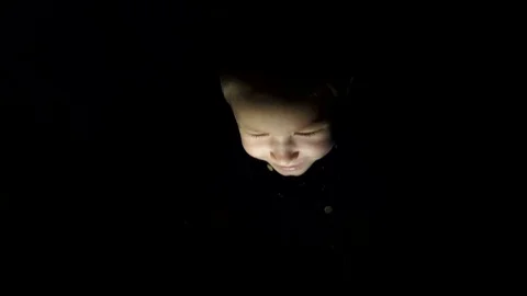 A child with a tablet in a dark room Stock Footage 74962226