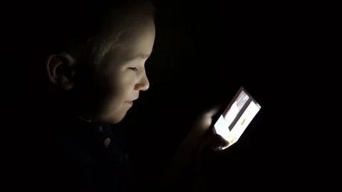 A child with a tablet in a dark room Stock Footage 74968324