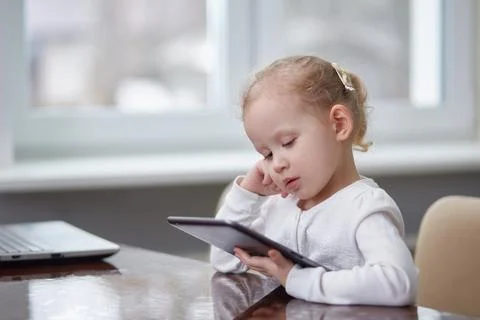Child with a tablet at the table. Copy space Stock Photos