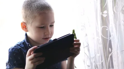 A child with a tablet, watching cartoons, smiling Stock Footage 74978088