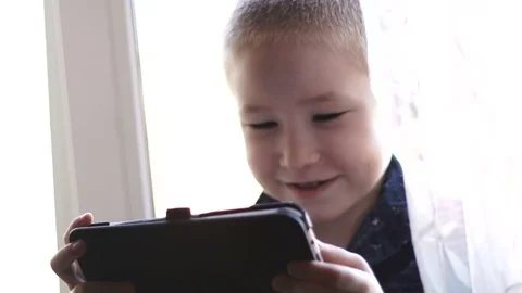 A child with a tablet, watching cartoons, smiling Stock Footage 74978223