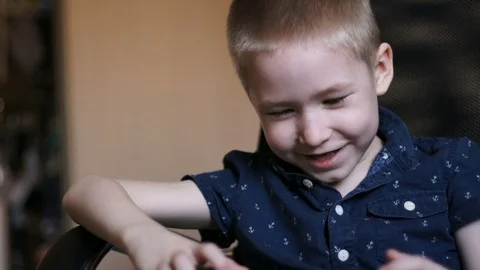 A child with a tablet, watching cartoons, smiling. Sits in an office chair Stock Footage 74980530
