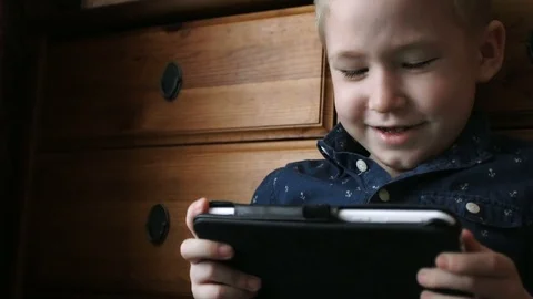 A child with a tablet, watching cartoons, smiling Stock Footage 74981570