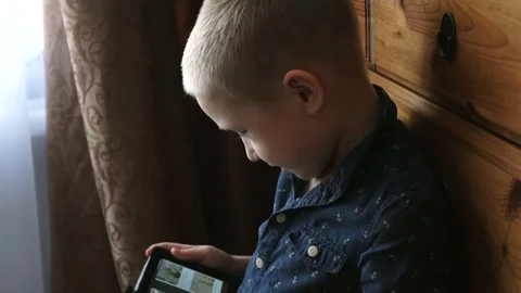A child with a tablet, watching cartoons, smiling Stock Footage 74981948