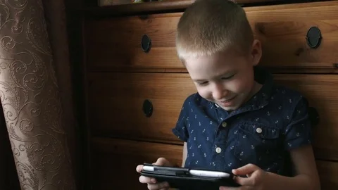 A child with a tablet, watching cartoons, smiling Stock Footage 74982232