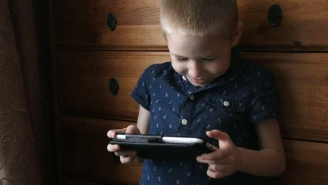 A child with a tablet, watching cartoons, smiling, slow motion Stock Footage 74987387