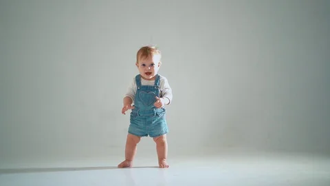 The child takes the first steps; he succeeds, but hesitates. studio slow moti Stock Footage 128247063