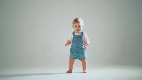 The child takes the first steps; he succeeds, but hesitates. studio slow moti Video stock 128247517
