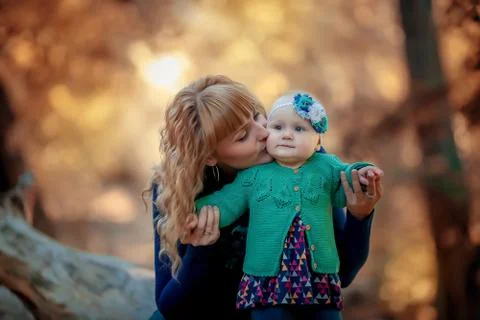 The child takes his first steps with the help of his mother in the fresh air in Stock Photos