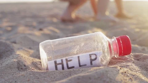 Child takes a plastic bottle with the message help lying from the sand Stock Footage 115310804