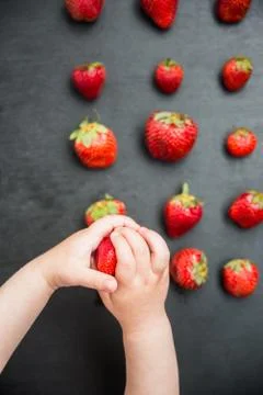 Child takes the strawberries with the black table Stock Photos