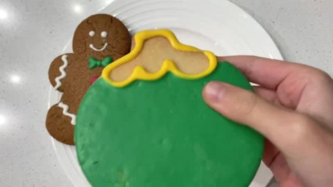 Child taking a bite out of a colorfully decorated holiday cookie shaped 動画素材 145634294