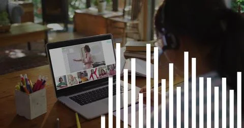Child taking notes in remote class while teacher speaking and laptop audio bars 스톡 사진