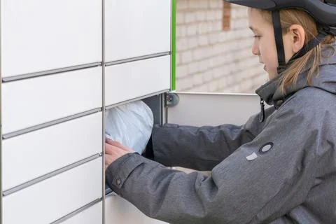 Child taking package from open parcel locker compartment outdoors. Stockfoto's