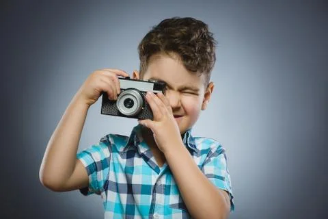 Child taking a picture using a retro rangefinder camera isolated grey background Foto stock
