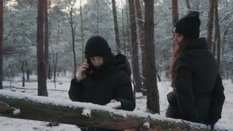 A child talking on a smartphone during a winter walk as their mother waits. 스톡 동영상 311886895