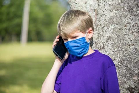 A child talks on cell phone while wearing a face mask during the coronavirus  Foto stock