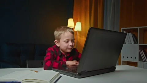 The child teaches lessons while at home sitting in the living room at the table Stock Footage 170132570