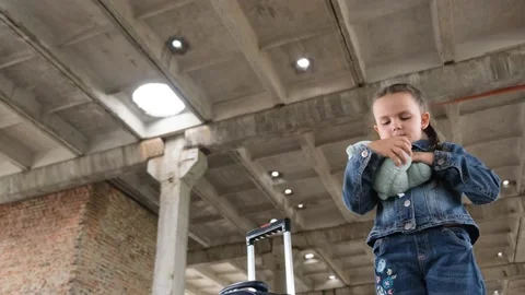 A child with a teddy bear in his hands in a building destroyed by rocket fire Vídeos de archivo 230016418