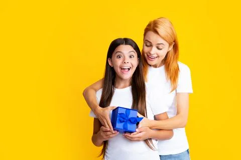 Child teen girl giving present to excited amazed mother isolated on yellow Stock Photos