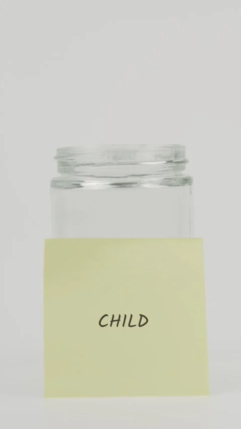 Child text or word on yellow sticky note attached to glass jar with hand Stock Footage 311691079