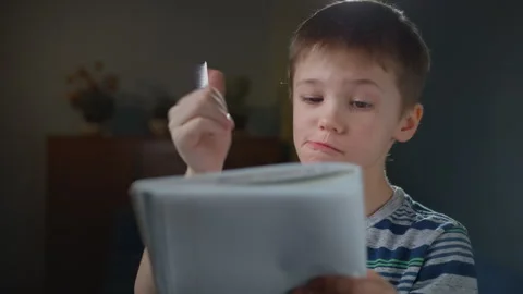 Child Thinking Hard, Then Smiling and Writing Solution in Notebook Stock Footage 302877524