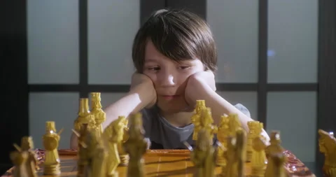 Child thinking move chess pieces next to handmade chessboard. Stock Footage 149196691