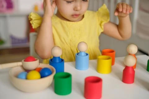 Child thinks how to perform a logical task with colored cups Stock Photos